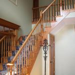 Before the transformation - This traditional entry staircase needed an update to the wooded balusters and floral carpet runner.